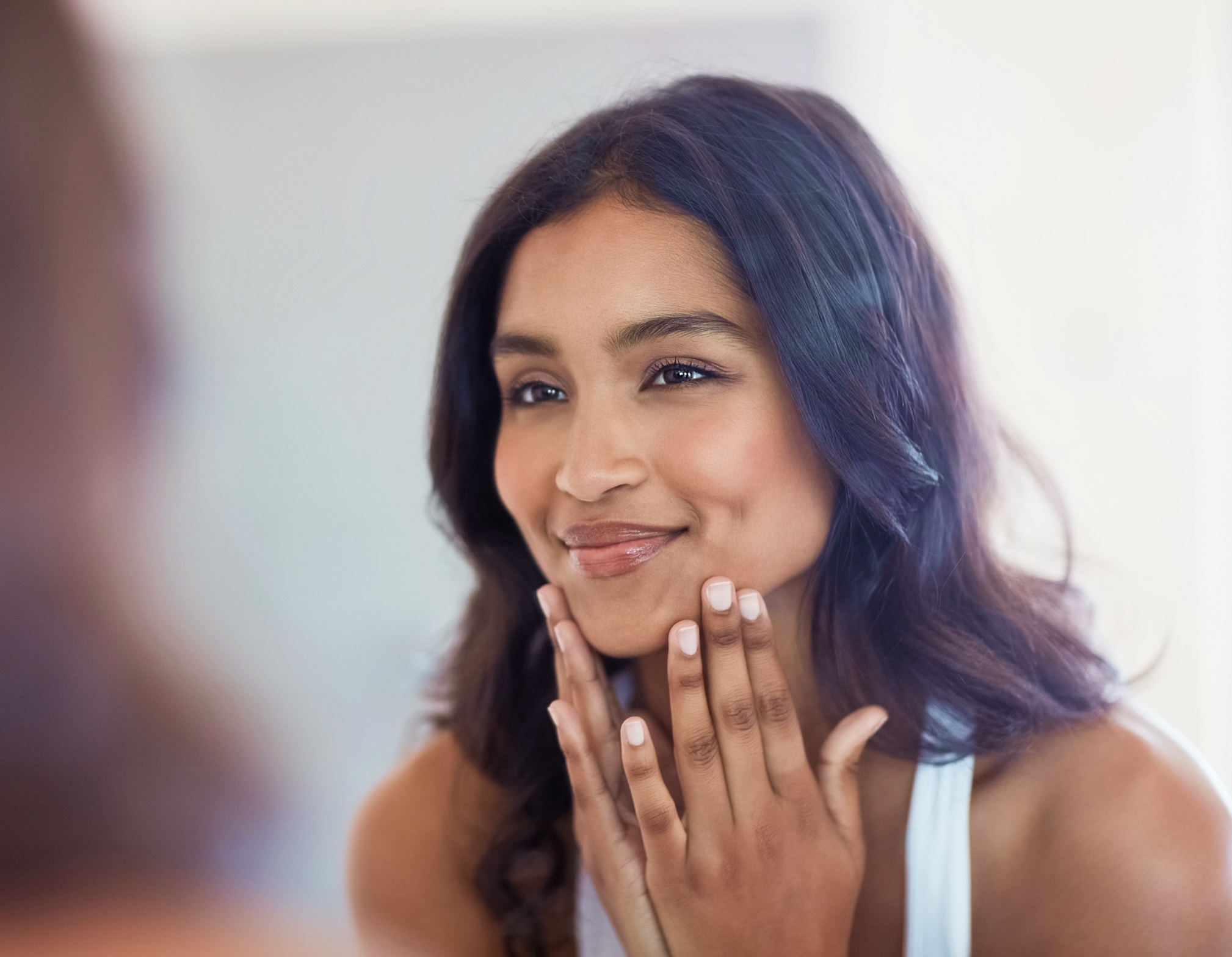 Woman looking at her face in the mirror